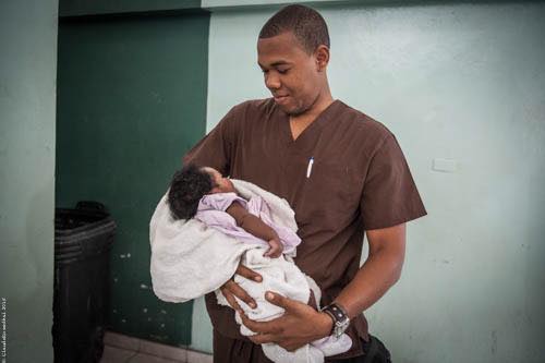 Un obstétricien haitien, formé par GSF, porte un bébé qu'il vient de mettre au monde, en Haiti. 